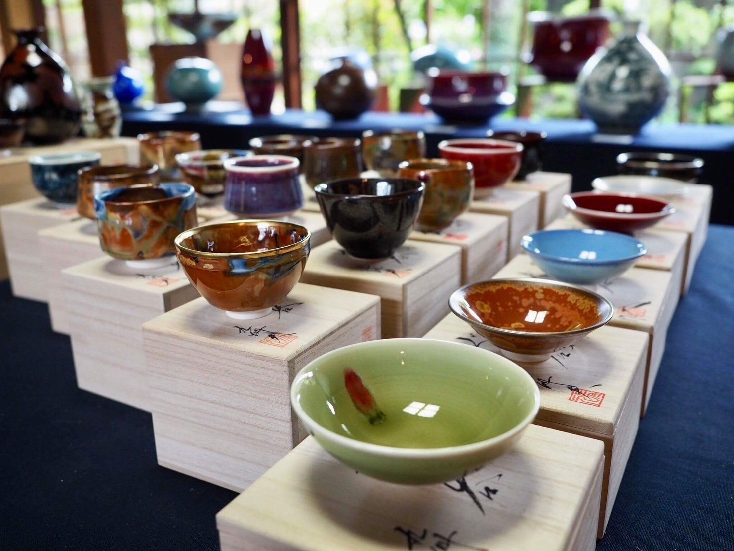 真右エ門窯による一点作ぐい呑みの集合体。辰砂の生命的な赤、藍染水滴の静謐な青、耀変天目の深淵な黒など、石の理性が1300度の炎の奇跡と出会い生まれた多様な「小宇宙」が並列している様。これらは単なる酒器の羅列ではなく、現代人の異なる魂の渇きを癒やし、精神を整える聖域（セラピー）としての選択肢が提示されている光景である。